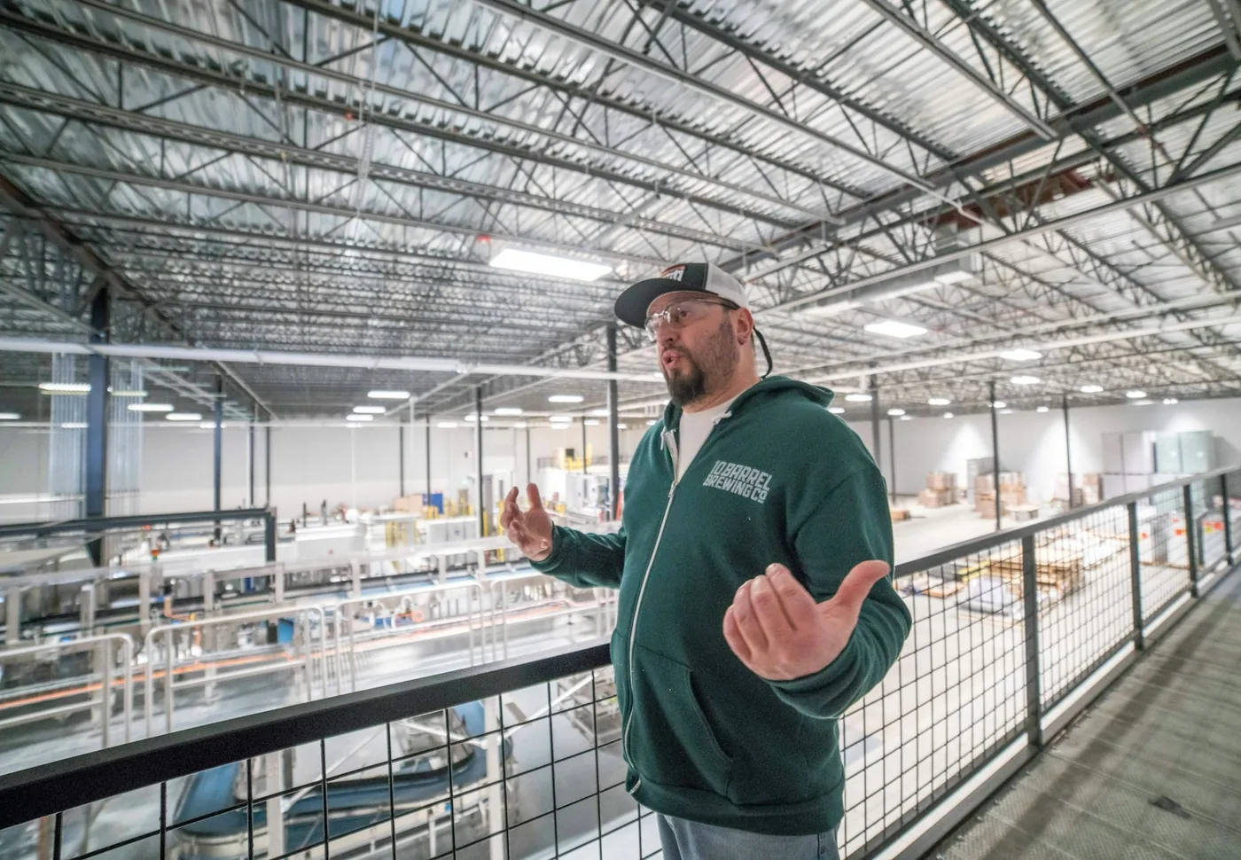 Plant manager talking to colleagues on a mezzanine above a manufacturing floor